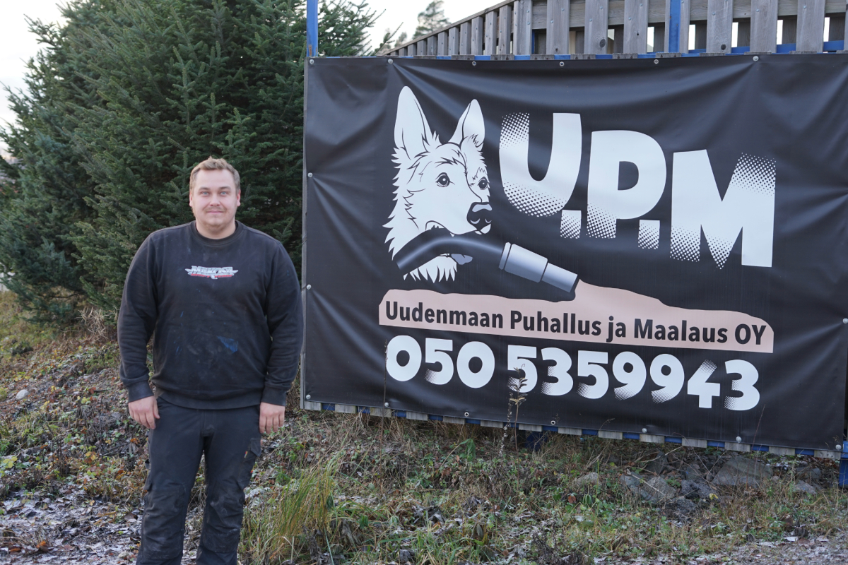 Yrittäjä Janne Mattila seisoo mainosbanderollin vieressä.