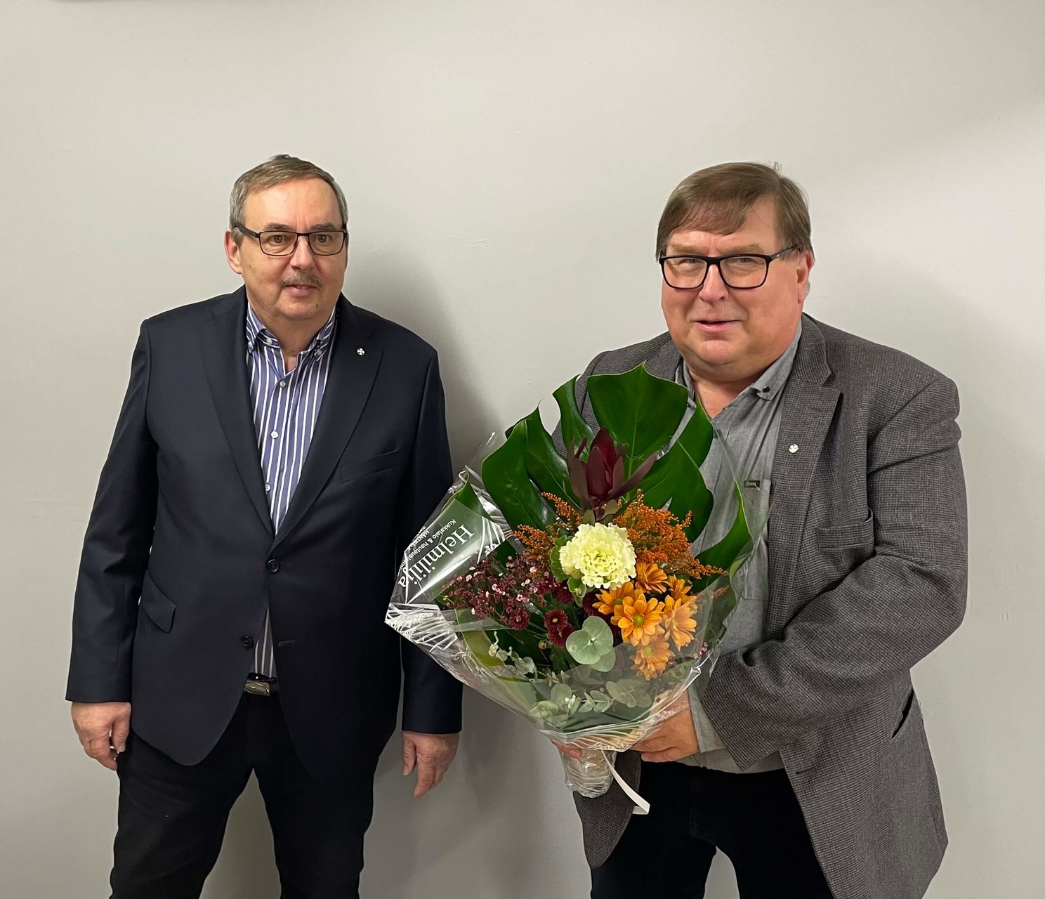 Vuoden 2023 Mäntsälän Yrittäjien puheenjohtaja Jarmo Mäkeläinen ja uusi Mäntsälän Yrittäjien puheenjohtaja Eero Kokko onnittelukukkien kanssa.
