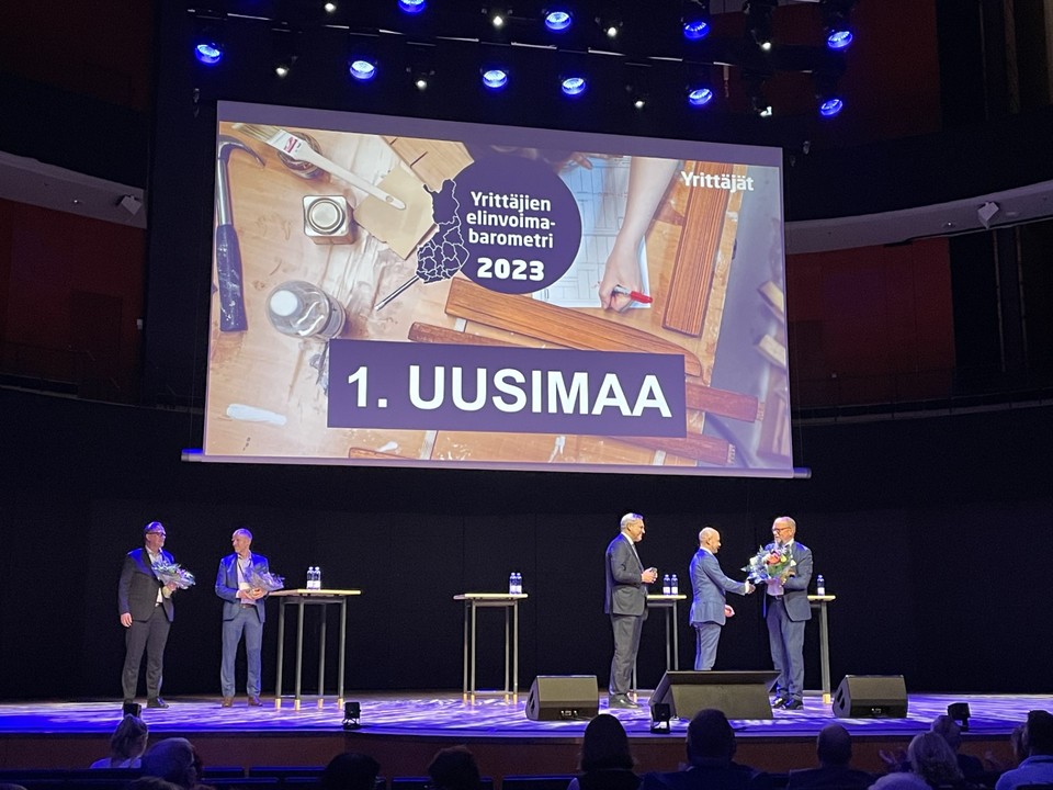 Vuoden 2023 elinvoimabarometrin palkinnon vastaanottaa lavalla Ossi Savolainen. Taustalla on dia Uudenmaan voitosta.